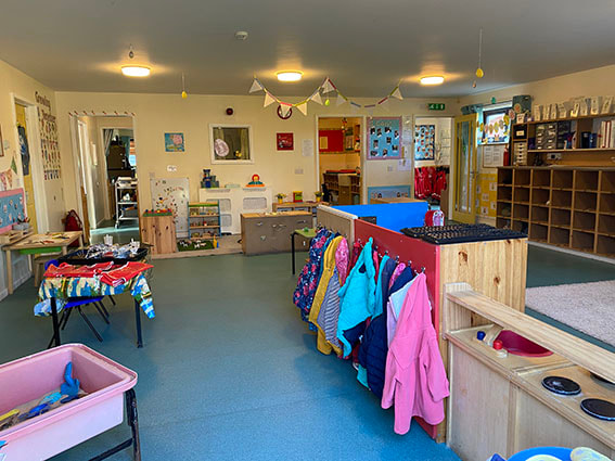 Children's coats hang ready beside craft tables at the Wymondham nursery