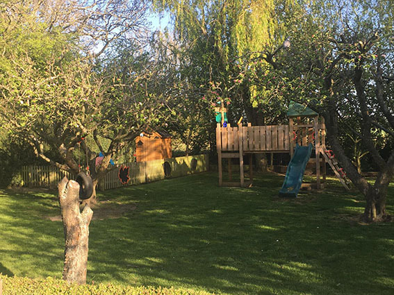 The climbing frame and slide nestled among apple trees at the Wymondham nursery