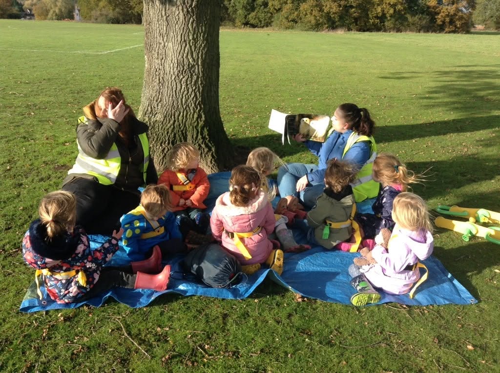 Children listening to a story outdoors under a tree