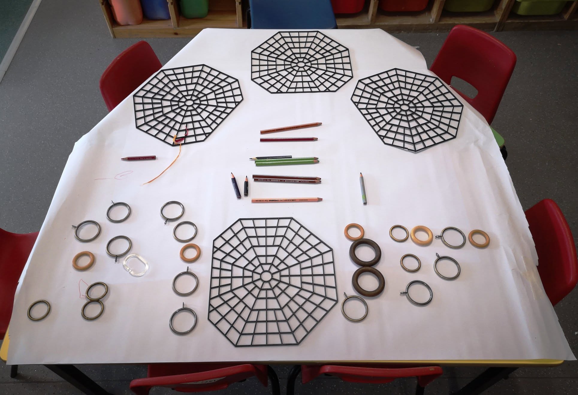 A creative activity table set with pencils, rings and web shapes