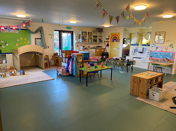 A colourful playroom with bunting and cosy reading nooks at the Wymondham nursery